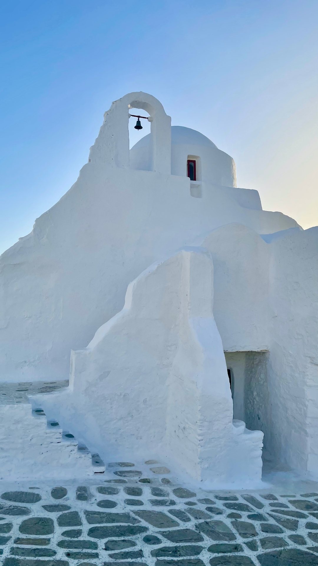 Witgekalkte Mykonos-kapel met klokkentoren bij avondlicht
